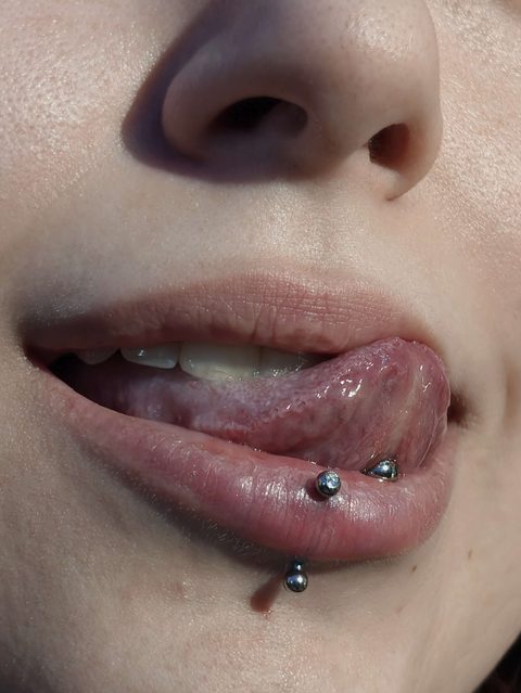 Tongue and lip piercings: a tongue bar and two lower lip studs
