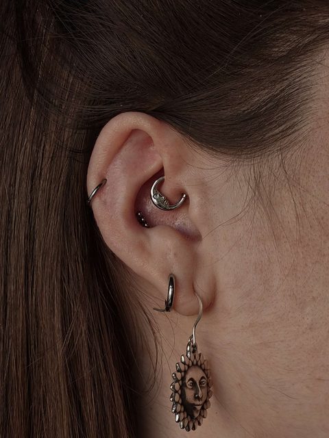 Ear with a daith ring, helix hoop and a sun charm on the lobe