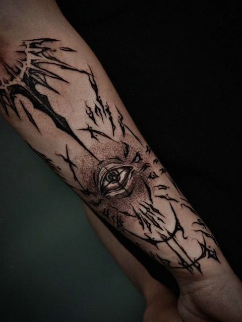 Forearm tattoo of an eye surrounded by thorny, dripping branches in black linework
