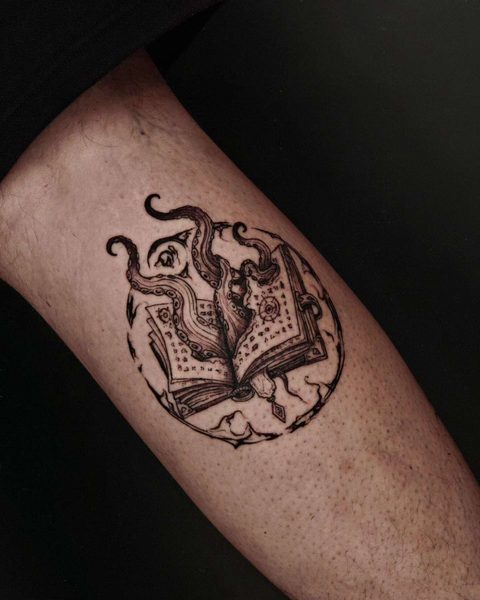 Circular tattoo of an open book with tentacles rising from its pages