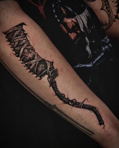 Forearm tattoo of a bandaged greatsword running the length of the arm